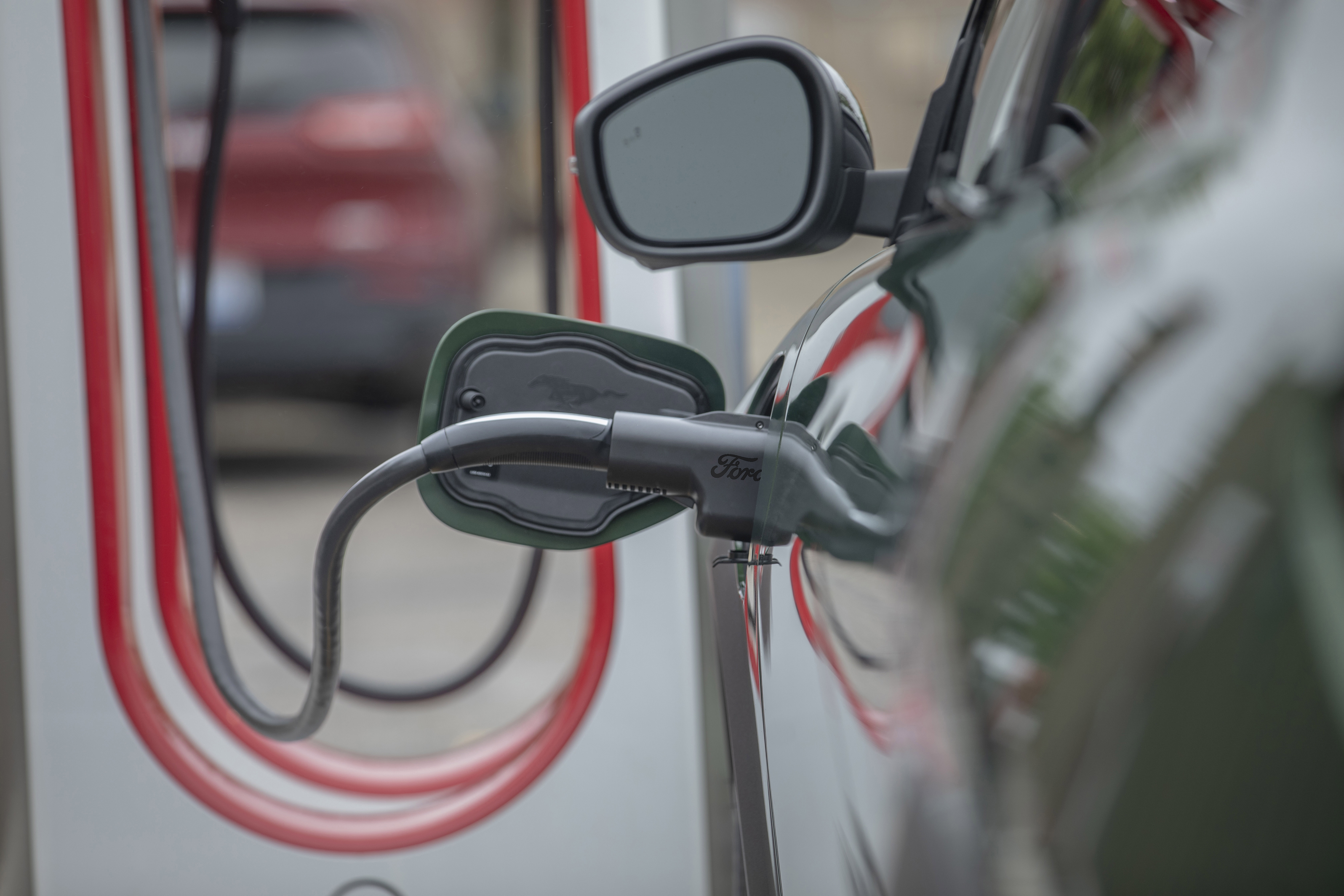 A Ford charging adapter is shown plugged into an electric vehicle.